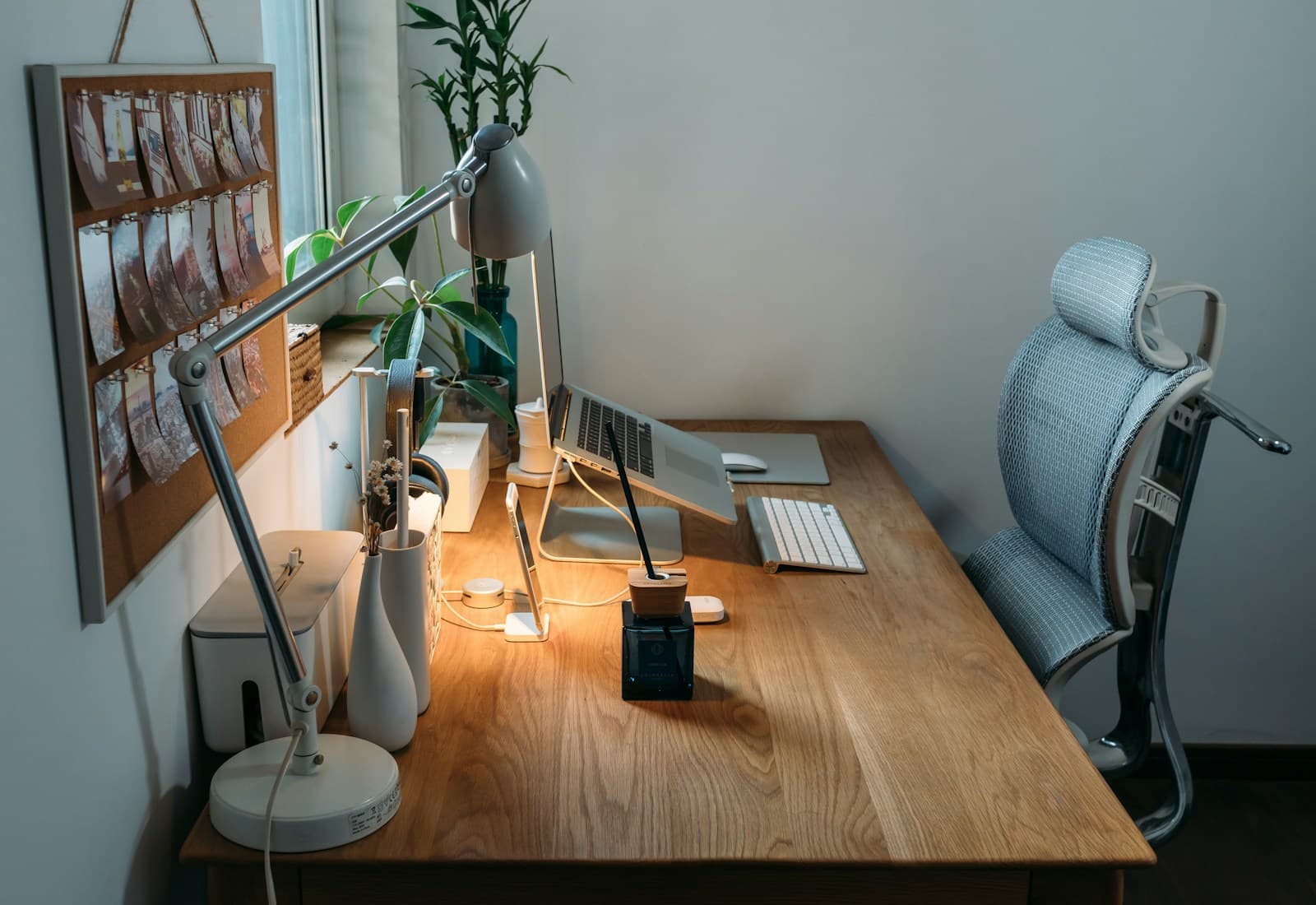 Adjustable grey task lamp illuminating a tidy wooden home-office desk